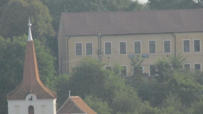 Az olthévízi református templom tornya. Háttérben a magyar nyelvű alsó tagozat épülete.